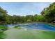 Outdoor tennis courts with green and blue surface surrounded by lush greenery on a bright day at 199 Eastham Ct, Suwanee, GA 30024