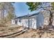 View of the home's rear, featuring light blue siding and a small patio area surrounded by trees at 2216 Marbut Farms Trce, Lithonia, GA 30058