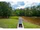 Backyard view featuring an outdoor grill, lush trees and a tranquil pond at 871 Cowan Se Rd, Conyers, GA 30094