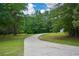 Concrete driveway with lush green grass and scattered trees at 871 Cowan Se Rd, Conyers, GA 30094