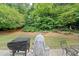 Well-maintained backyard with a patio, barbecue, lush landscaping, and a wooded backdrop at 1865 Morgans Run Trl, Buford, GA 30519