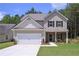 Charming two-story home showcasing a well-manicured lawn, a two-car garage, and a welcoming stone-accented entrance at 48 Beaver Pt, Villa Rica, GA 30180