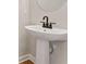 Elegant powder room featuring a pedestal sink, round mirror, and hardwood floors at 105 Priestwood Ln, Acworth, GA 30102