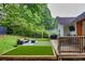 Backyard features a custom-built deck, artificial grass, grill, and a secluded area perfect for relaxing and entertaining outdoors at 575 E Main St, Buford, GA 30518