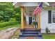Inviting front porch featuring a welcome mat, wooden posts, and American flag perfect for relaxing at 575 E Main St, Buford, GA 30518
