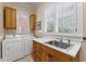 Functional laundry room featuring white appliances, wooden cabinets, a sink, and natural light at 585 Old Cobblestone Dr, Atlanta, GA 30350