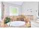Bathroom with tiled walls, a soaking tub next to a window and a glass enclosed shower to the left at 1379 Branchwood Dr, Snellville, GA 30078