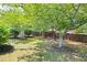 A fenced backyard with mature trees, green grass and a wooden swing under the shade at 4527 Baker Grove Nw Rd, Acworth, GA 30101