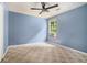 This cozy bedroom features patterned carpeting, soft blue walls, and a ceiling fan at 5292 Windfield Glen Nw Ct, Lilburn, GA 30047
