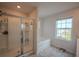 Modern bathroom featuring a glass-enclosed shower and a soaking tub under a window at 6827 Chataran Dr, Lithia Springs, GA 30122