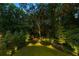 Private backyard featuring lush greenery, manicured lawns, landscape lighting, and mature trees at 803 Courtenay Ne Dr, Atlanta, GA 30306