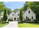 Charming two-story white home featuring manicured landscaping, a curved driveway, and a beautiful arched wooden front door at 803 Courtenay Ne Dr, Atlanta, GA 30306
