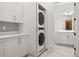Efficient laundry room with stacked washer/dryer, white cabinets, and view into the primary bathroom at 803 Courtenay Ne Dr, Atlanta, GA 30306