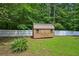 Backyard features a wooden storage shed, enclosed with a white fence and green lawn at 6201 Davids Se Way, Acworth, GA 30102