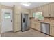 Bright kitchen features stainless steel refrigerator, neutral tile backsplash, and light colored cabinets at 115 Creek Cir, Stockbridge, GA 30281