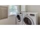 Laundry room with modern washer and dryer units, cabinet, and window at 5930 Bridle Dr, Cumming, GA 30028