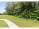 Spacious backyard with green grass, tall trees, and a walkway at 1565 Briergate Dr, Duluth, GA 30097