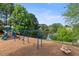 Community playground with swings, slide, and play structures next to a serene pond at 1565 Briergate Dr, Duluth, GA 30097