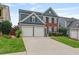 Inviting two-story home featuring a brick facade, blue siding, a well-manicured lawn, and a spacious two-car garage at 4312 Shillham Ct, Cumming, GA 30040