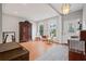 Bright living room featuring hardwood floors, a decorative armoire, neutral walls, large windows, and elegant lighting fixture at 4312 Shillham Ct, Cumming, GA 30040