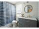 Charming bathroom with blue vanity, marble countertop, patterned shower curtain, and round mirror at 117 Village Ct, Woodstock, GA 30188