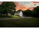 Charming home featuring a spacious front yard, attached garage, and lovely porch, set against a colorful sunset sky at 117 Village Ct, Woodstock, GA 30188