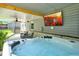 Relaxing covered patio with a large hot tub, comfortable seating, and mounted television at 117 Village Ct, Woodstock, GA 30188