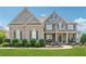 Beautiful two-story brick home with a manicured lawn, flower beds, and a covered front porch with seating at 5070 Laurel Ridge Dr, Cumming, GA 30040