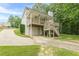 Rear view showing a spacious deck, staircase, garage and driveway surrounded by mature trees at 9707 Squirrel Wood Run, Douglasville, GA 30135