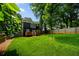 Spacious backyard with green lawn, black two-story home, privacy fence, and mature trees at 1558 Line St, Decatur, GA 30032