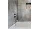 Modern bathroom showcasing gray tiled walls, bathtub with chrome fixtures, and built-in storage shelf at 1558 Line St, Decatur, GA 30032