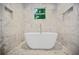 Bright bathroom features a modern standalone tub, marble tile walls, and a window with tree views at 1558 Line St, Decatur, GA 30032