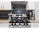 The kitchen boasts a gas range with a pot filler and dark subway tile backsplash at 1558 Line St, Decatur, GA 30032