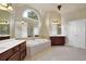 Bathroom featuring dual vanities, a large bathtub, tiled floors, and mirrors reflecting ample natural light at 6260 Sturbridge Ln, Cumming, GA 30040