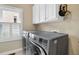 Convenient laundry room featuring modern washer and dryer, storage cabinets, and natural light from a window at 6260 Sturbridge Ln, Cumming, GA 30040