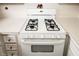 Close up of a white 4-burner gas range stove with white counters and white cabinets at 1200 Ashborough Se Ter # A, Marietta, GA 30067