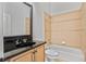 Bathroom with tiled bathtub, toilet, and vanity with black countertop and wood cabinet at 5513 Lavender Farms Rd, Powder Springs, GA 30127