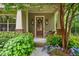 Inviting front porch with a rustic wooden door framed by blooming hydrangeas and charming exterior lighting at 1184 Medlin Se St, Smyrna, GA 30080