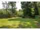 A large grassy backyard, surrounded by a wooden fence and mature trees at 178 Mayson Ne Ave, Atlanta, GA 30307