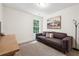 Bright, minimalist bedroom with light grey sofa, neutral walls, carpet, and a window with a lush tree view at 2357 Heritage Park Nw Cir # 17, Kennesaw, GA 30144