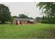 A lush green backyard featuring a cozy patio and a classic brick home with vibrant red accents at 5488 Janice Ln, Stone Mountain, GA 30087