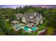 Aerial twilight view of backyard with in-ground pool, patio, lush landscaping, and trees at 710 Cox Rd, Roswell, GA 30075