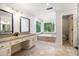 Bathroom featuring double sinks, a soaking tub, and large windows offering serene views of the outdoors at 8255 Habersham Waters Rd, Atlanta, GA 30350