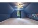 Cozy bedroom with blue walls, carpeted floors, and a window overlooking the backyard at 8255 Habersham Waters Rd, Atlanta, GA 30350