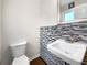 Half bath features modern horizontal tiled accent wall and an ornate beveled mirror at 145 Washington St, Mcdonough, GA 30253