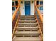 A detailed view of the home's entry stairs leading up to a covered front porch with a vibrant blue door at 112 Village Ct, Woodstock, GA 30188