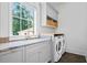Well-lit laundry room with gray cabinets, marble counters, built-in shelves, and modern washer and dryer at 3146 Frontenac Ne Ct, Atlanta, GA 30319
