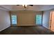 Large primary bedroom with tray ceiling, carpet floors, and natural light at 6385 Southland Forest Dr, Stone Mountain, GA 30087