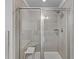 Modern bathroom shower with glass doors, a built-in seat, and neutral tile at 4568 Mantova Dr, Buford, GA 30519