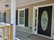 A close-up of the front door with a decorative glass panel, framed by black shutters and a covered porch at 105 Old Hickory Pointe, Mcdonough, GA 30252